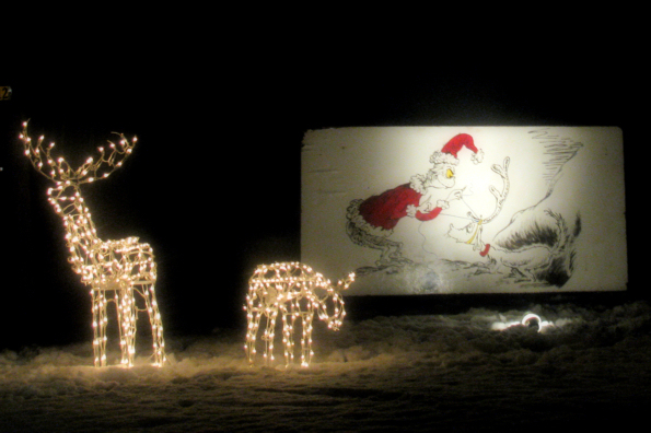 The Grinch and his dog on a "card" with lit dear in the yard.