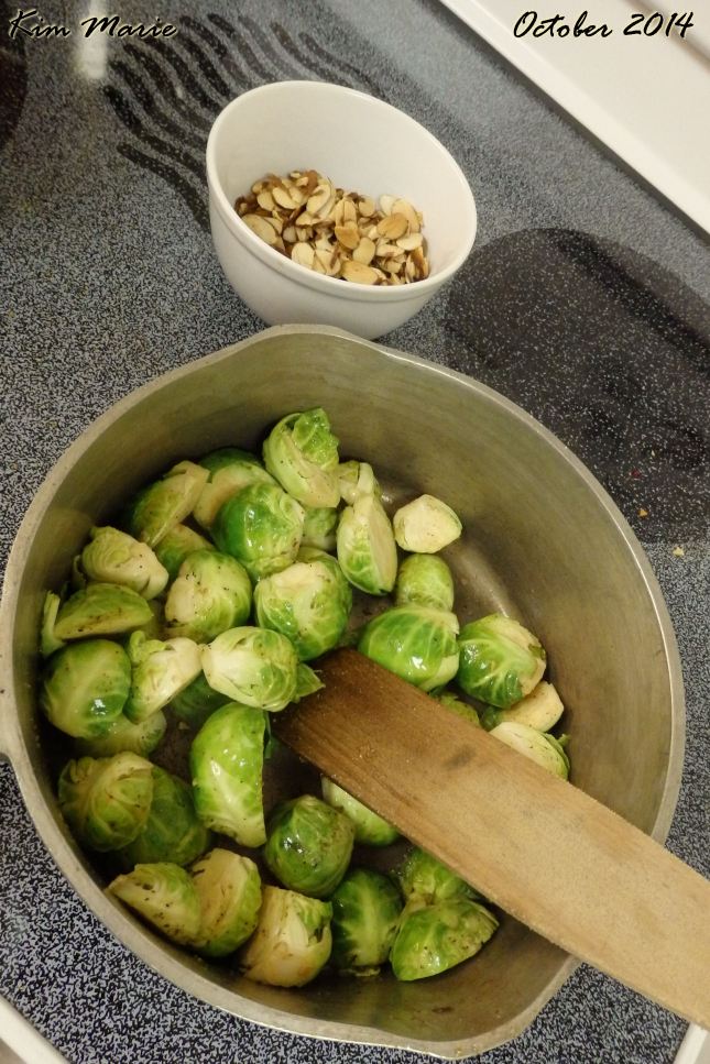 Brussels Sprouts in a pan being prepared and a side dish of nuts to include in the dish.