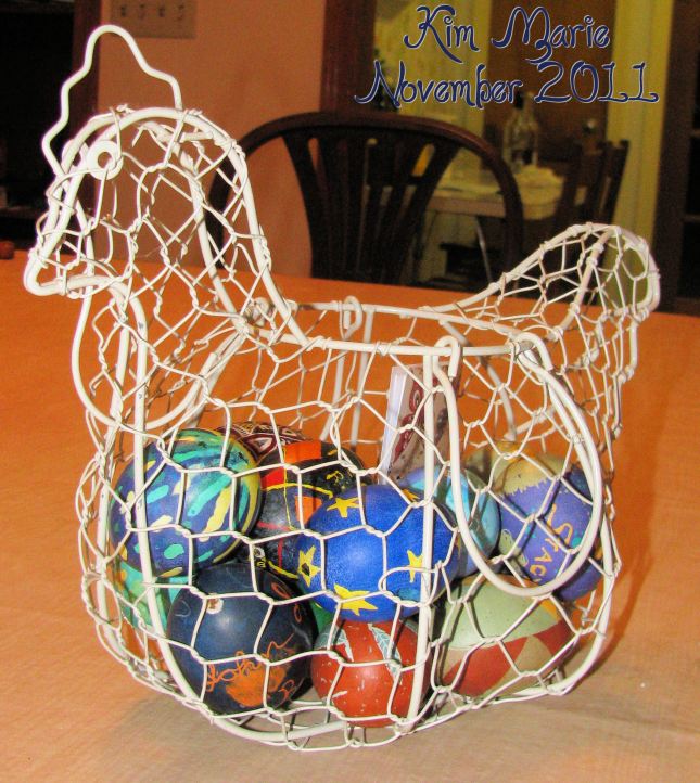 Wire chicken basket with Pysanky dyed eggs inside - mostly blues and greens with some reds.