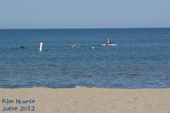 Two yellow swim caps way out yonder, swimming for a triathlon. 